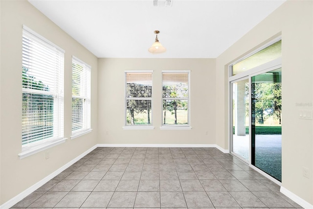 spare room featuring light tile patterned flooring and a healthy amount of sunlight