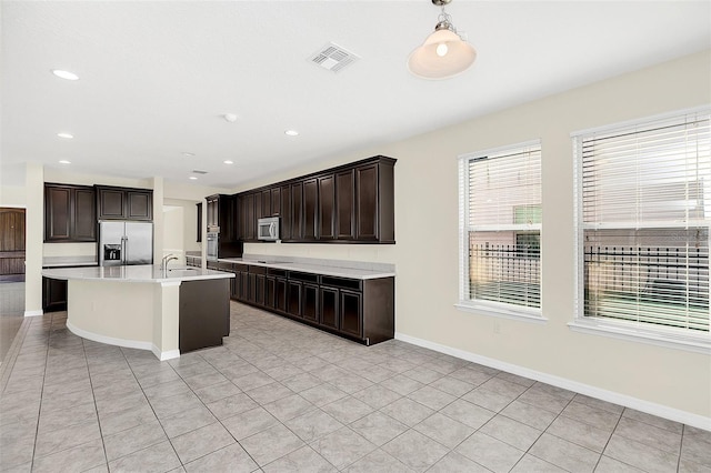 kitchen featuring pendant lighting, light tile patterned flooring, dark brown cabinetry, and appliances with stainless steel finishes