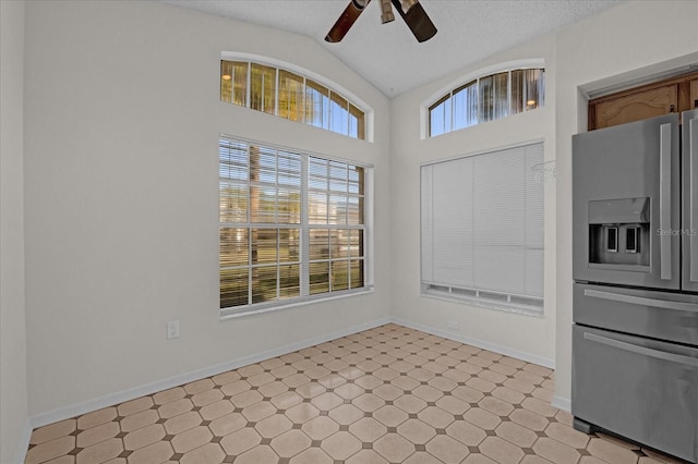 unfurnished dining area featuring ceiling fan, lofted ceiling, and a textured ceiling