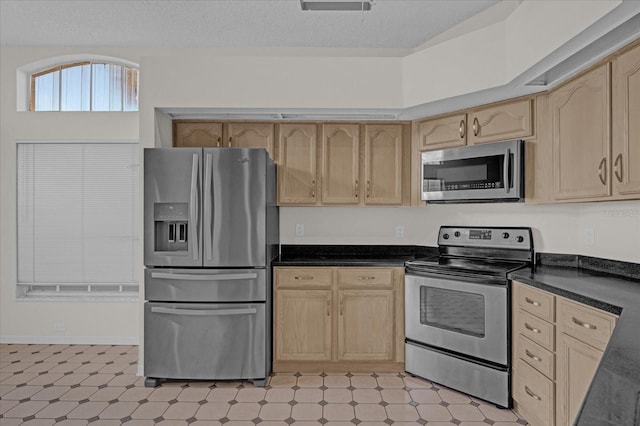 kitchen with appliances with stainless steel finishes, light brown cabinets, and a textured ceiling