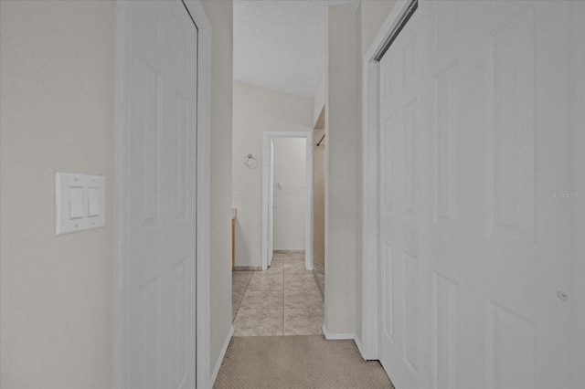 corridor featuring light tile patterned floors and lofted ceiling