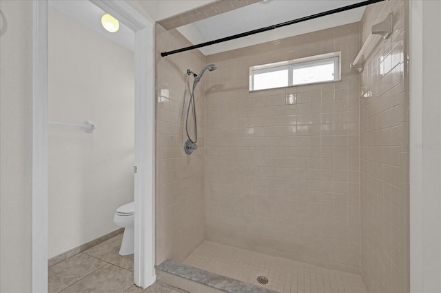 bathroom featuring tiled shower, tile patterned flooring, and toilet