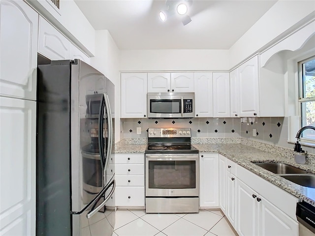 kitchen with backsplash, sink, light stone countertops, appliances with stainless steel finishes, and white cabinetry