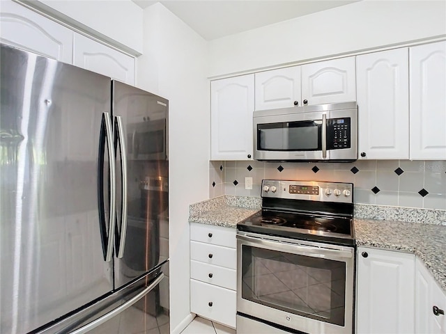 kitchen featuring white cabinets, appliances with stainless steel finishes, tasteful backsplash, and light stone counters