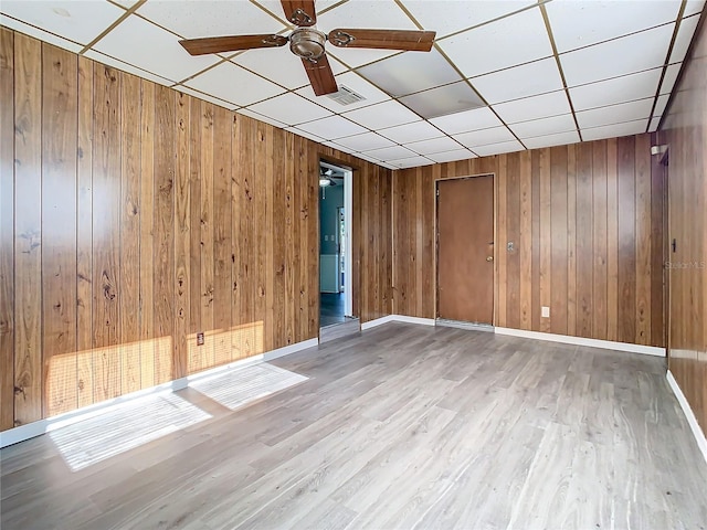 empty room featuring ceiling fan, a drop ceiling, and light hardwood / wood-style floors