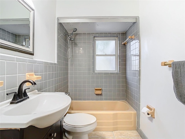 full bathroom with vanity, tile patterned flooring, tiled shower / bath combo, toilet, and tile walls