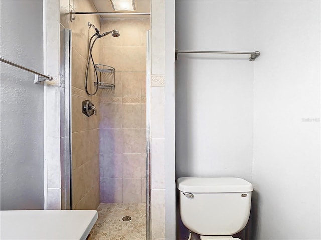 bathroom featuring toilet and a tile shower