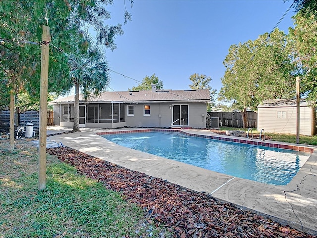 view of swimming pool with a sunroom, a shed, and a patio