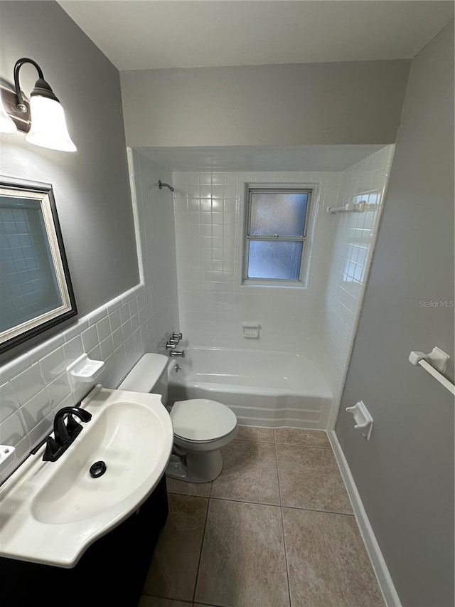 bathroom with tile walls, toilet, a sink,  shower combination, and tile patterned flooring