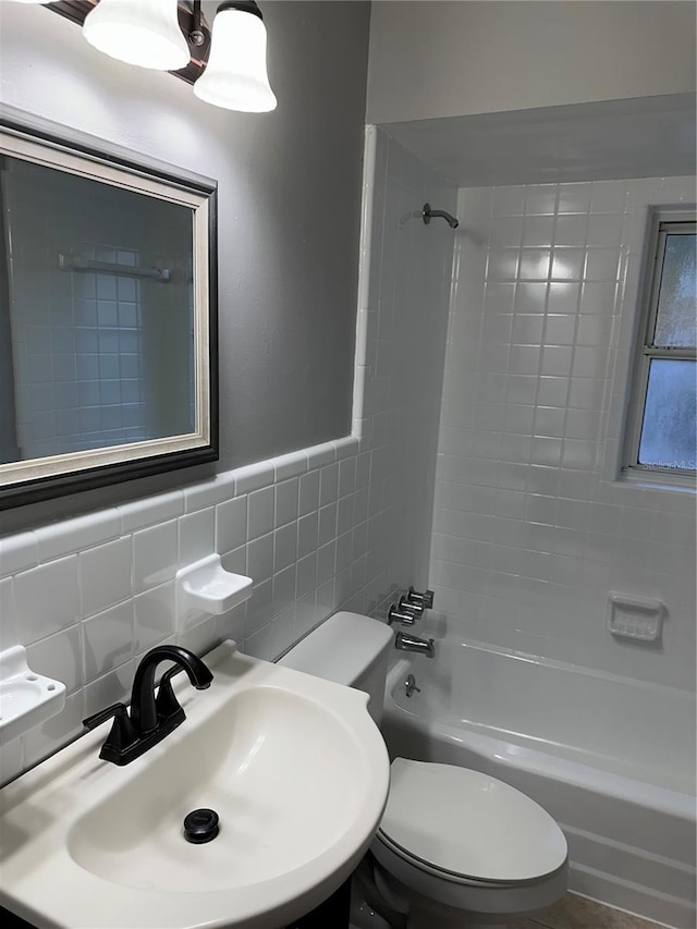 full bath with toilet, a sink, tile walls, and shower / tub combination