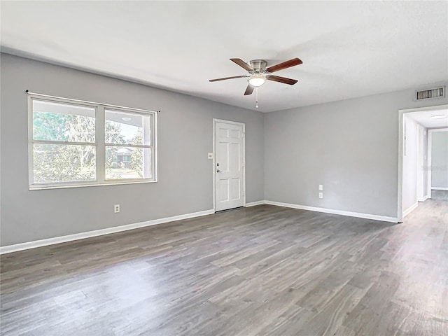 spare room featuring baseboards, visible vents, and dark wood-type flooring