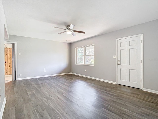 unfurnished room with ceiling fan, dark wood finished floors, and baseboards