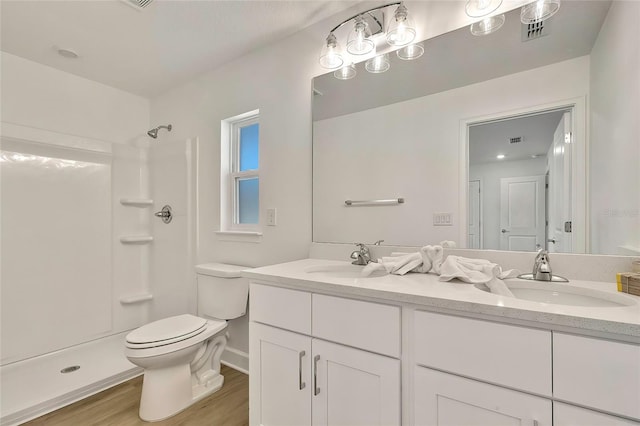 bathroom with a shower, vanity, wood-type flooring, and toilet