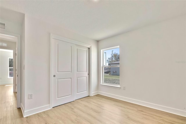 unfurnished bedroom with a textured ceiling, light hardwood / wood-style floors, and a closet