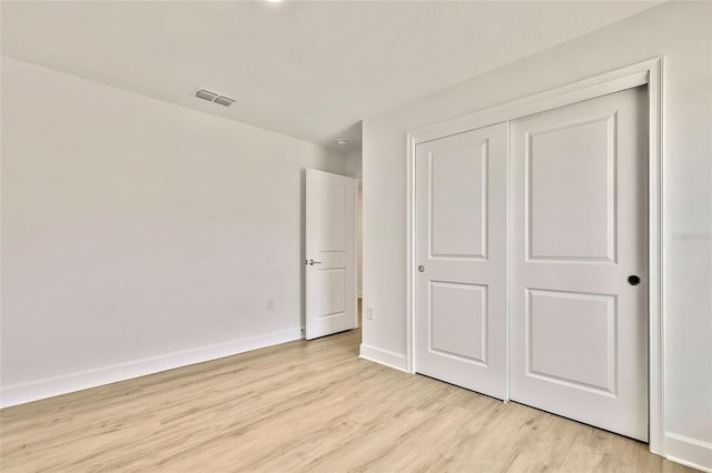 unfurnished bedroom with light hardwood / wood-style flooring and a closet