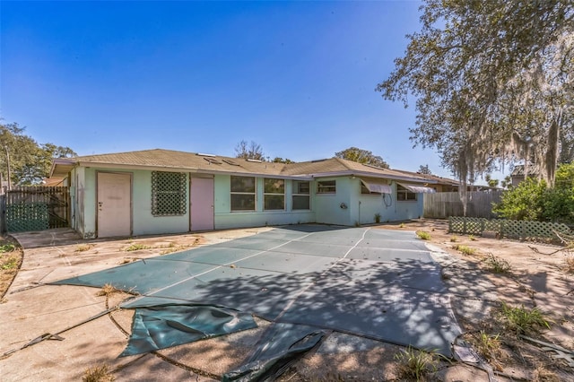 rear view of property with a patio area and a covered pool