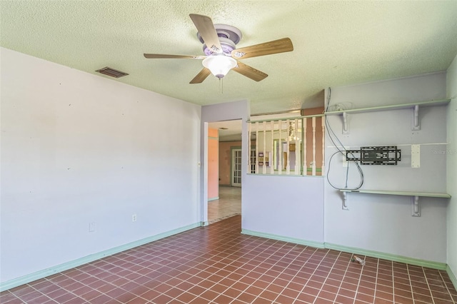 empty room with a textured ceiling, tile patterned floors, and ceiling fan