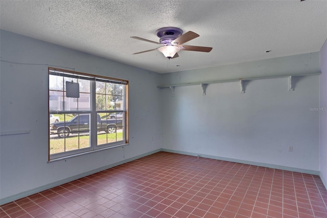 empty room featuring ceiling fan, light tile patterned flooring, and a textured ceiling