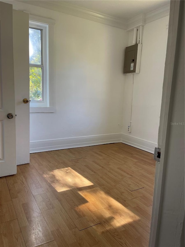 unfurnished room featuring electric panel, hardwood / wood-style flooring, and ornamental molding