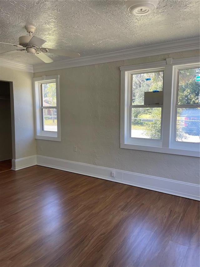 empty room with a textured ceiling, ornamental molding, and dark wood-type flooring