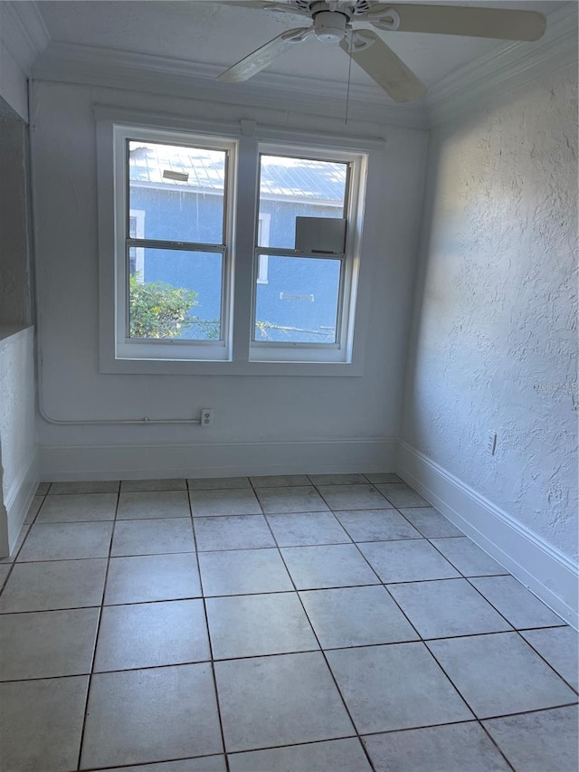 tiled empty room with ceiling fan and ornamental molding