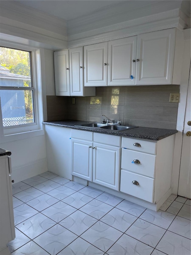 kitchen with decorative backsplash, light tile patterned floors, white cabinetry, and sink