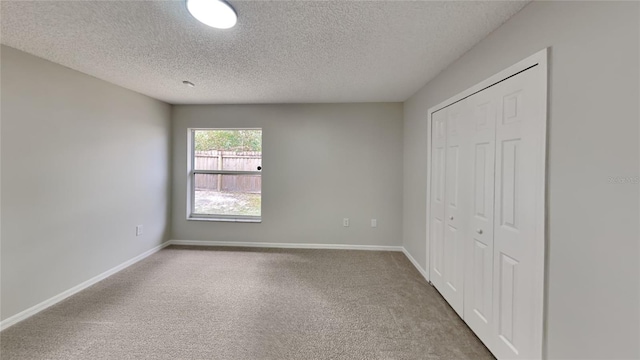 unfurnished bedroom featuring a textured ceiling, carpet floors, and a closet