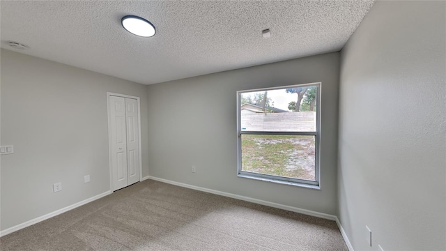 carpeted empty room with a textured ceiling