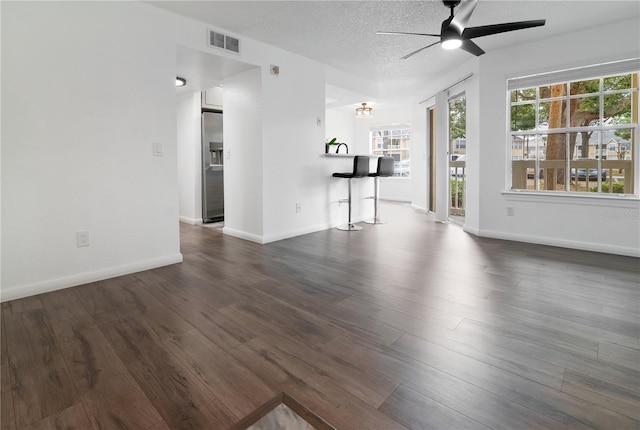 unfurnished living room with ceiling fan, dark wood-type flooring, and a textured ceiling