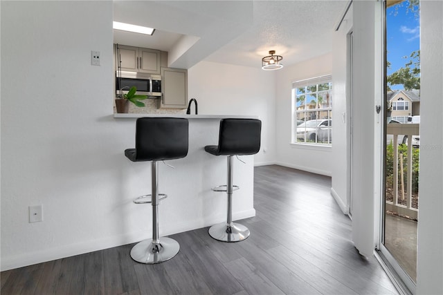 kitchen featuring gray cabinetry, dark wood-type flooring, a kitchen breakfast bar, sink, and a textured ceiling