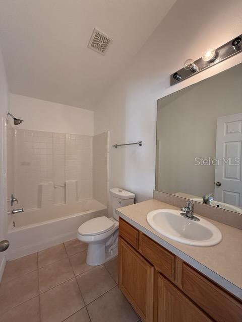 full bathroom featuring tile patterned floors, lofted ceiling, toilet, shower / washtub combination, and vanity