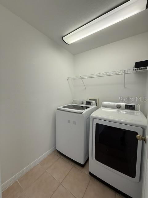 laundry room with light tile patterned flooring and washing machine and clothes dryer