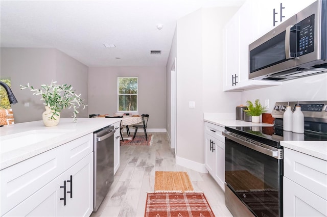 kitchen with white cabinets, stainless steel appliances, and light hardwood / wood-style flooring