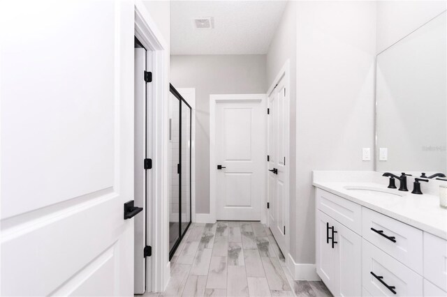 bathroom featuring vanity, a shower with shower door, a textured ceiling, and hardwood / wood-style flooring