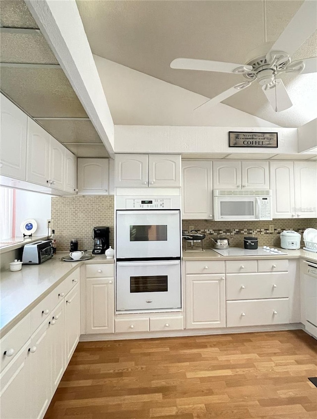 kitchen with decorative backsplash, white appliances, vaulted ceiling, light hardwood / wood-style flooring, and white cabinets