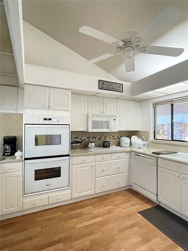 kitchen with white cabinetry, tasteful backsplash, light hardwood / wood-style flooring, lofted ceiling, and white appliances