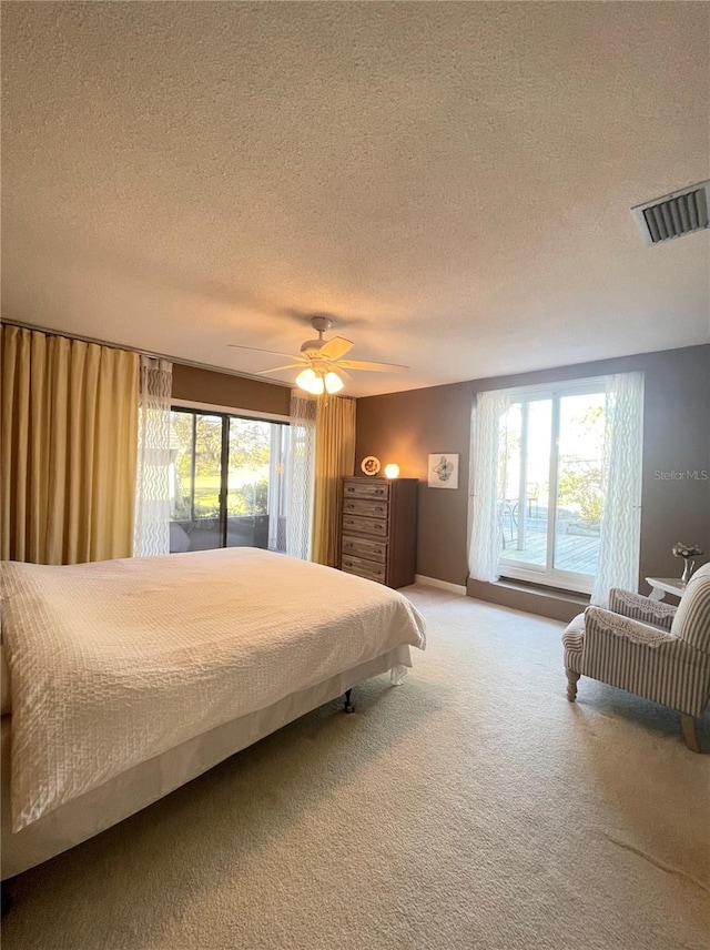 carpeted bedroom with a textured ceiling, multiple windows, and ceiling fan