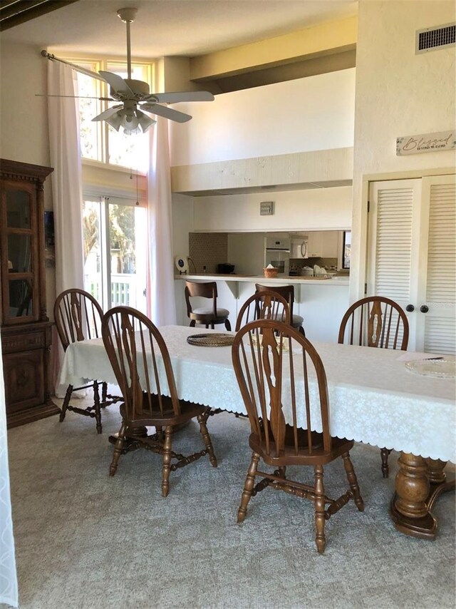 dining space featuring carpet flooring, beam ceiling, and ceiling fan