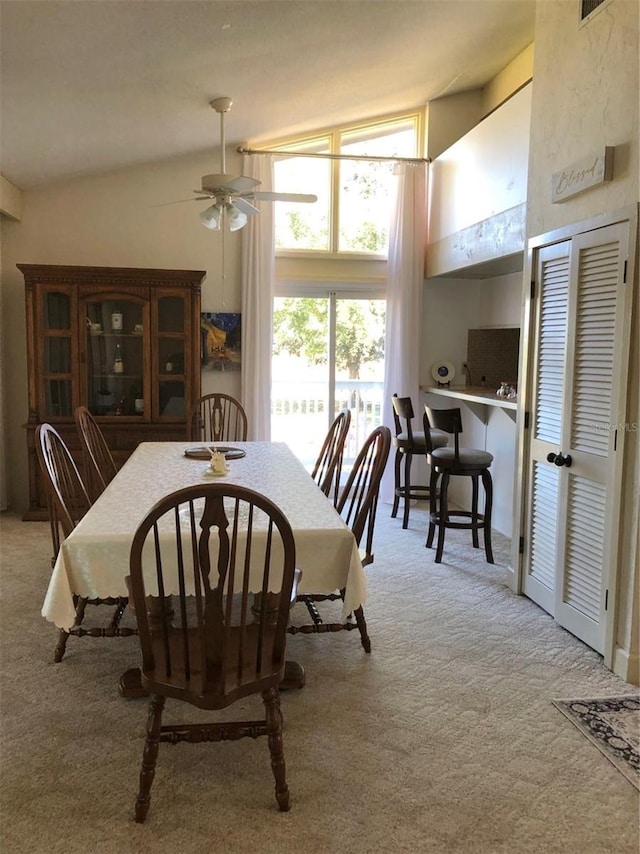 dining space featuring light carpet, ceiling fan, and lofted ceiling