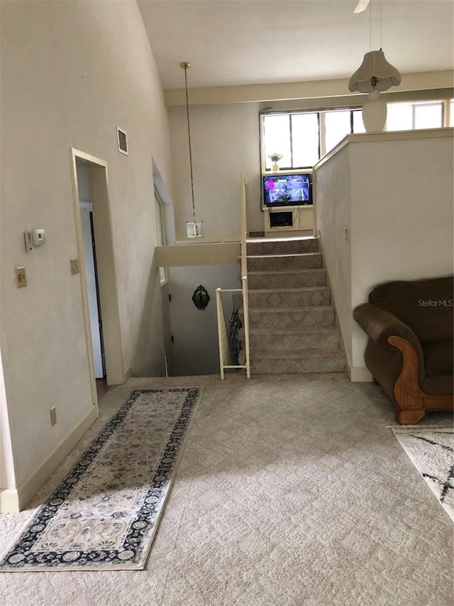 staircase with carpet, a towering ceiling, and plenty of natural light