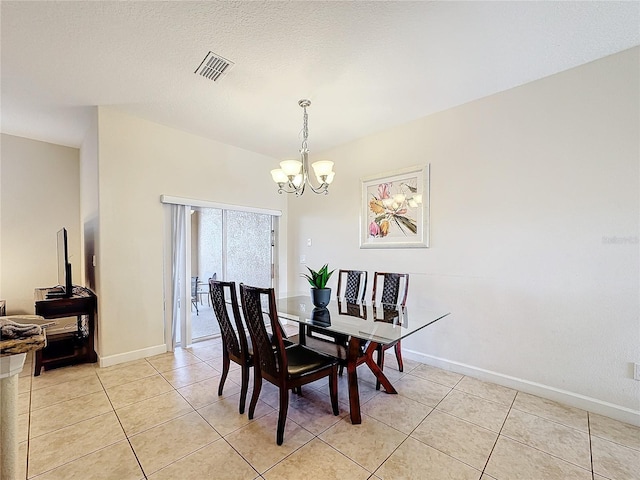 dining area featuring light tile patterned floors, a textured ceiling, and an inviting chandelier