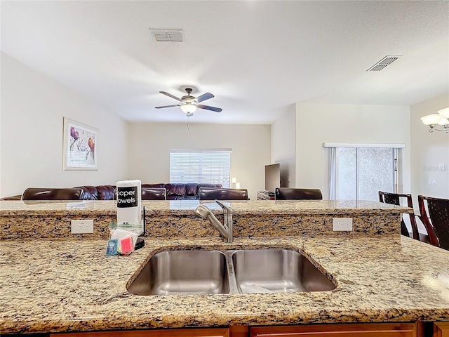 kitchen with light stone countertops, sink, and a chandelier