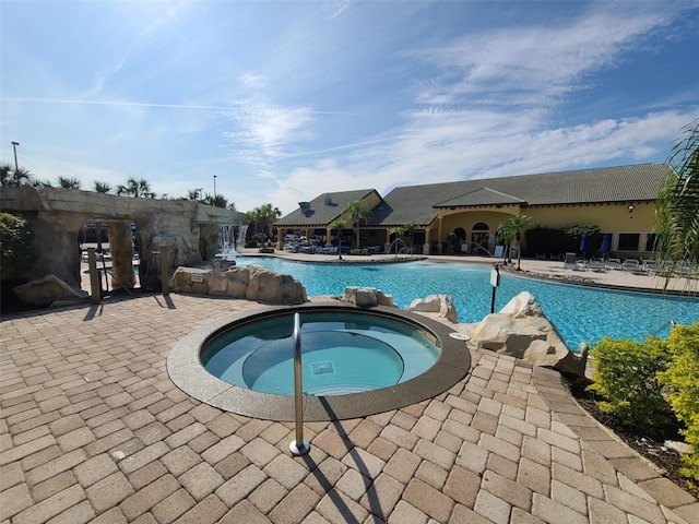 view of swimming pool with a patio, pool water feature, and a hot tub