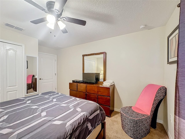 bedroom featuring light carpet, a textured ceiling, a closet, and ceiling fan