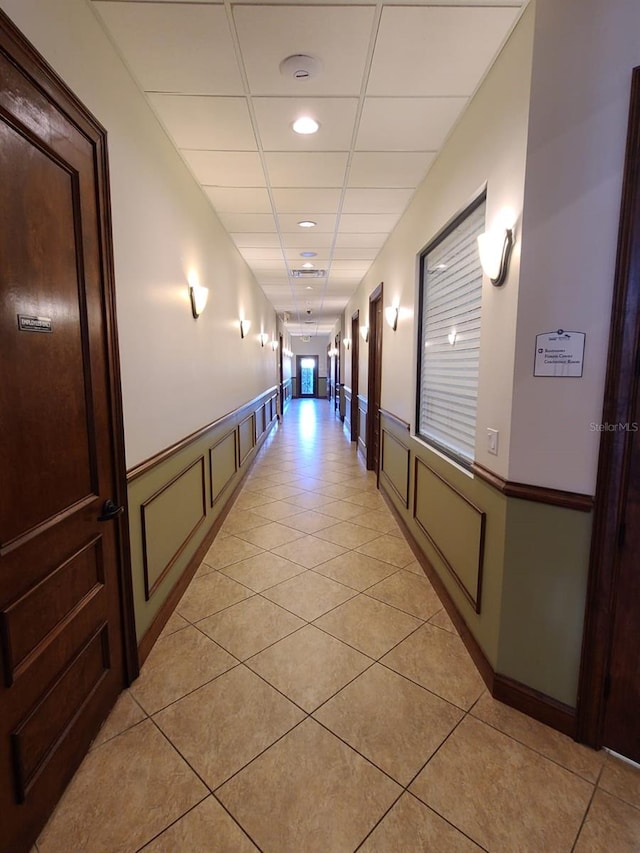 corridor with a drop ceiling and light tile patterned floors