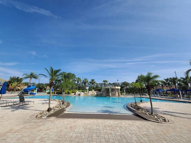 view of pool with a patio area, pool water feature, and a water slide