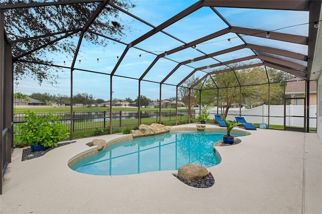 view of swimming pool with glass enclosure, a patio area, and a water view