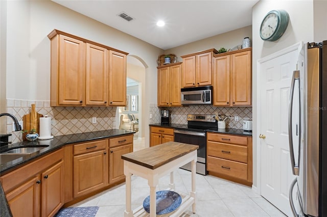 kitchen with tasteful backsplash, sink, light tile patterned floors, and appliances with stainless steel finishes