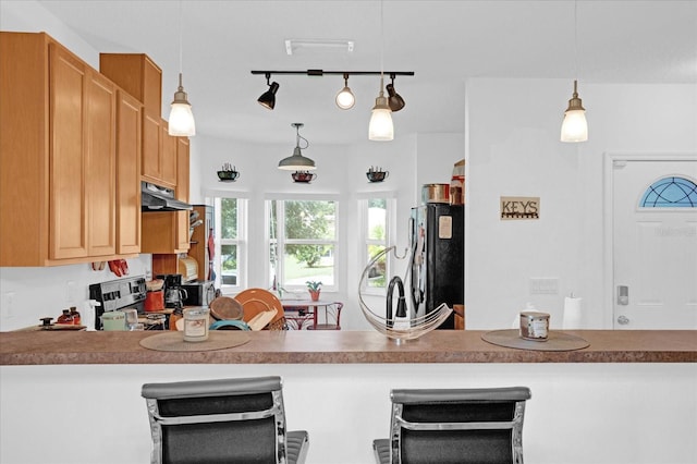 kitchen featuring black refrigerator, rail lighting, stainless steel range, and hanging light fixtures