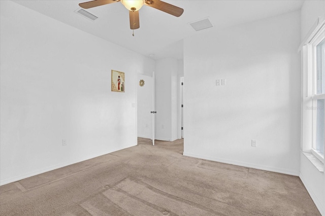 spare room featuring ceiling fan, light colored carpet, and a wealth of natural light